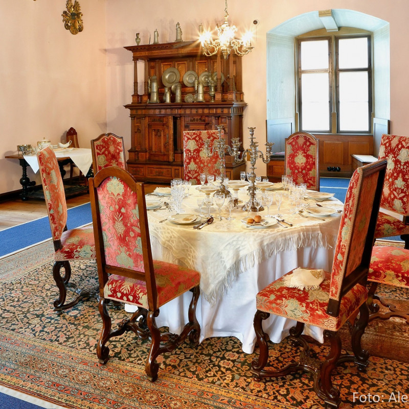 In der Mitte des Salons steht eine gro&szlig;z&uuml;gige Sitzgruppe. An den W&auml;nden stehen Schreibtisch, Schrank und Kommoden.