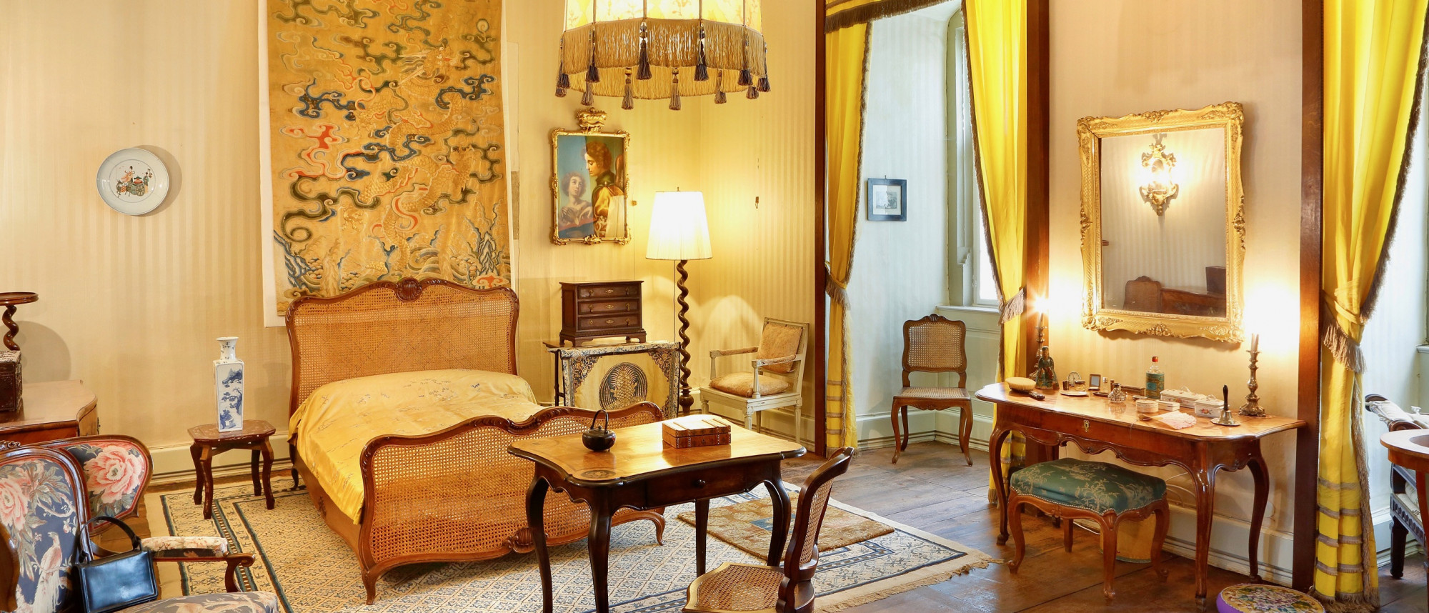 Raumansicht des Schlafzimmers von Carola Gräfin von Luxburg. Die Einrichtung ist in Gelbtönen gehalten.