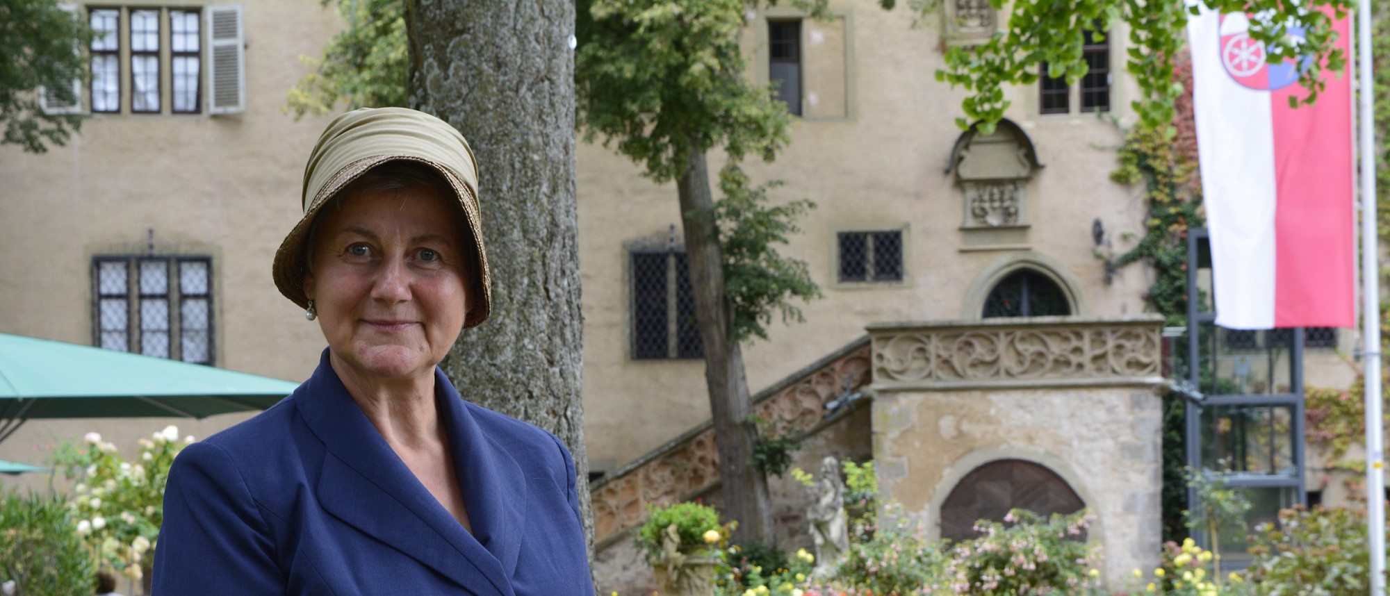 Eine Museumspädagogin hat sich als Gräfin Carola verkleidet. Im Hintergrund befindet sich das Schloss.