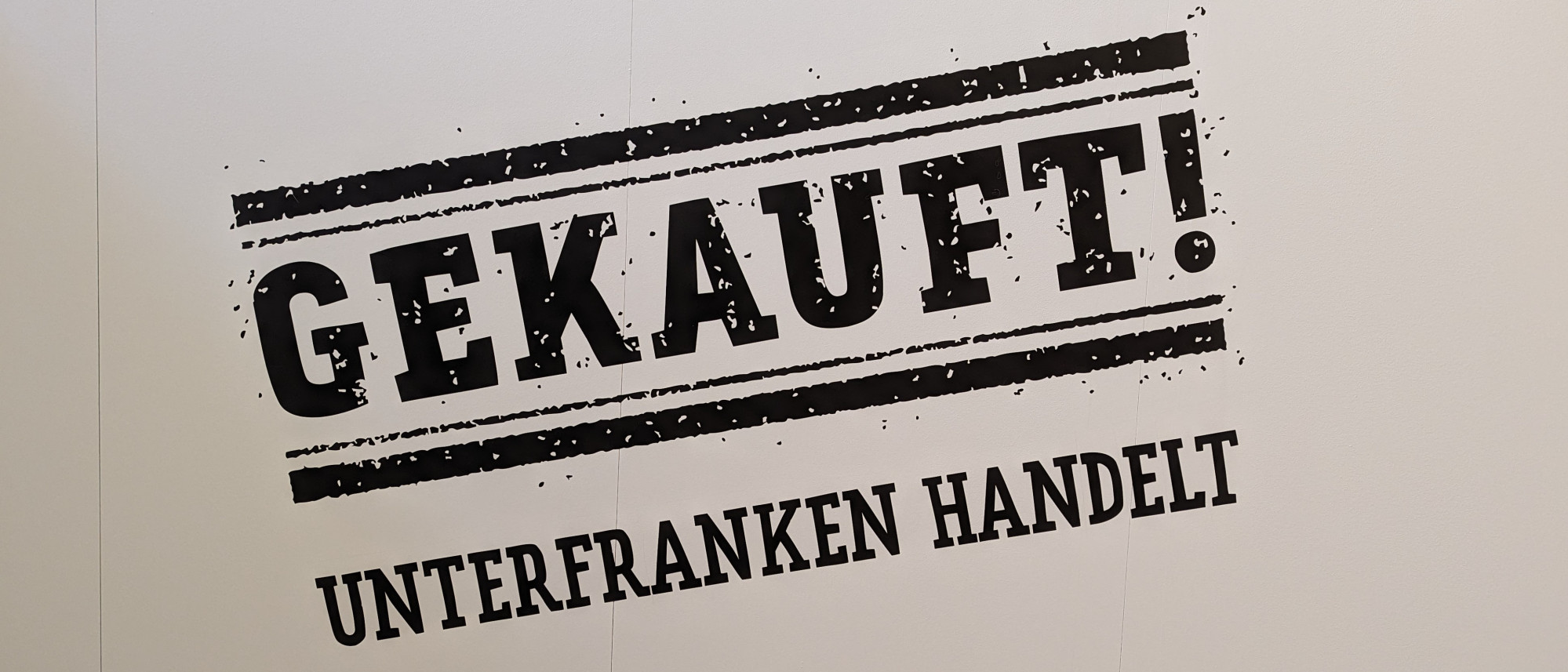 In schwarzer Schrift steht auf weißem Grund: GEKAUFT! UNTERFRANKEN HANDELT